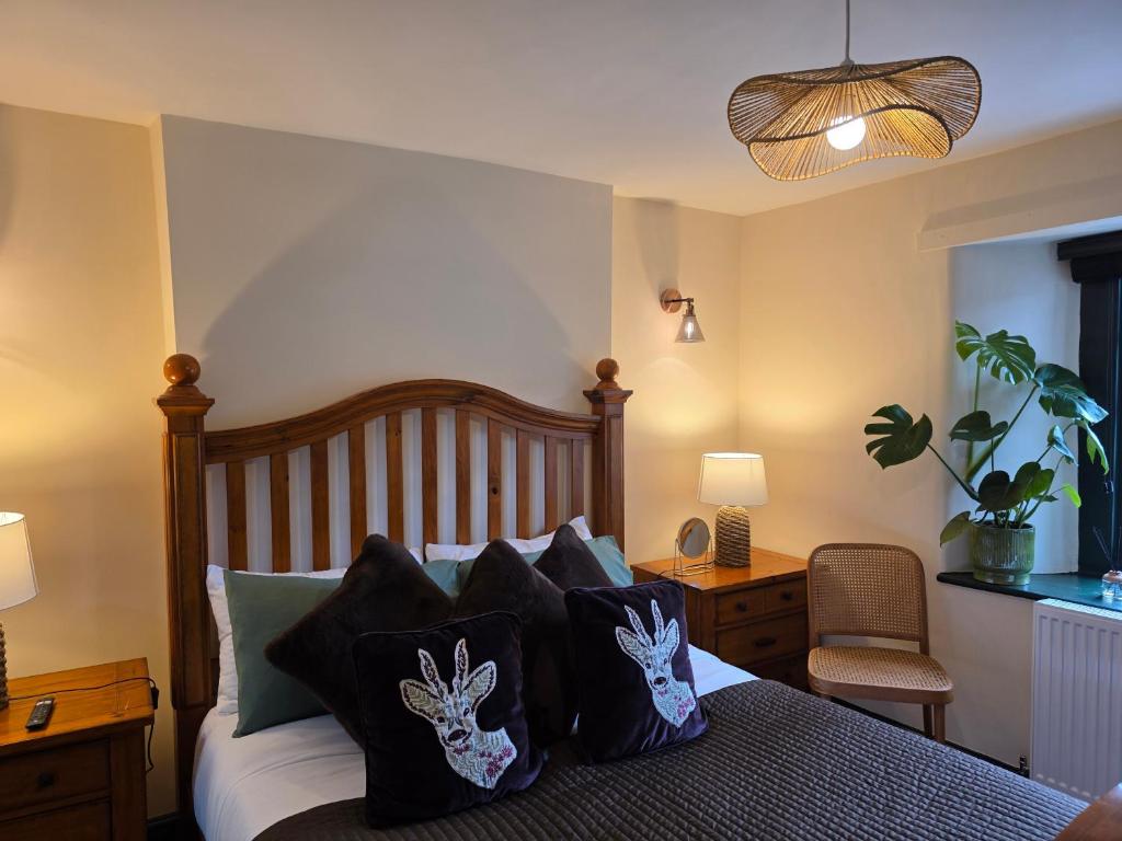 The Classic Room — bedroom with wooden headboard, deer cushions, monstera plant, and rattan pendant